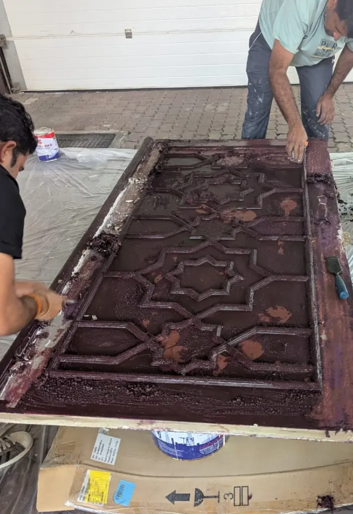 Expert carpenter and painter polishing and repairing a damaged door surface in a Dubai villa